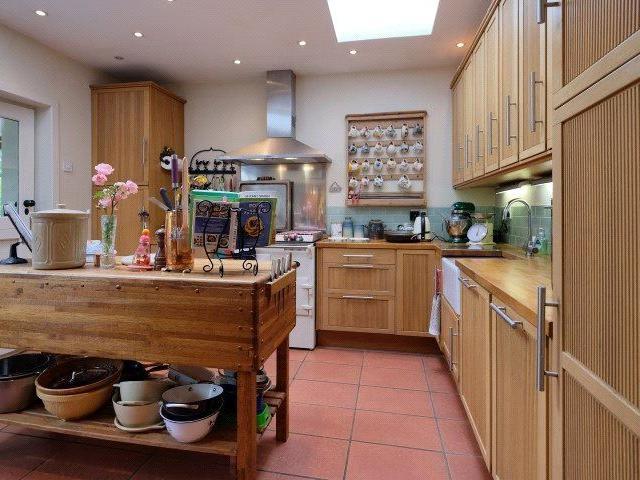 The kitchen has an island, a Belfast sink, and an integrated dishwasher.